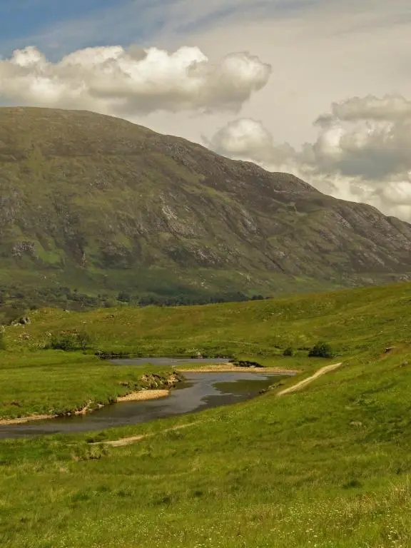 a river in a field with a mountain in the background at Park Guest House in Inverness