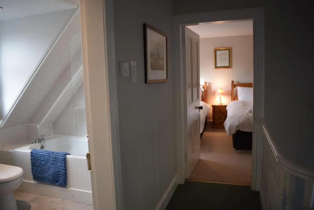a hallway with a bathroom with a tub and a bed at 3 St Gilbert Street in Dornoch