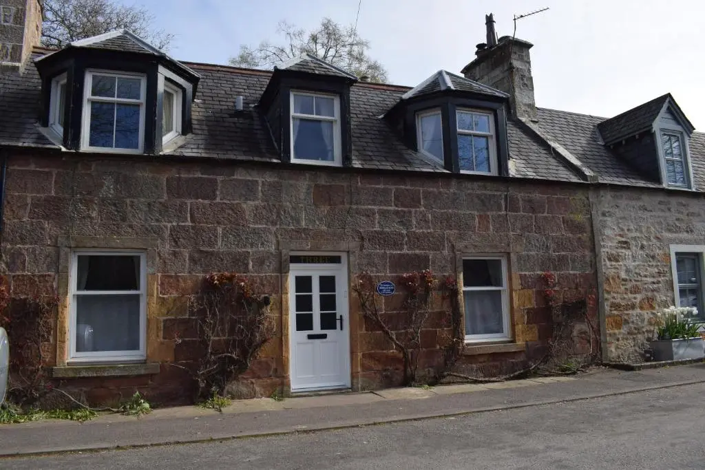 an old brick house with a white door at 3 St Gilbert Street in Dornoch