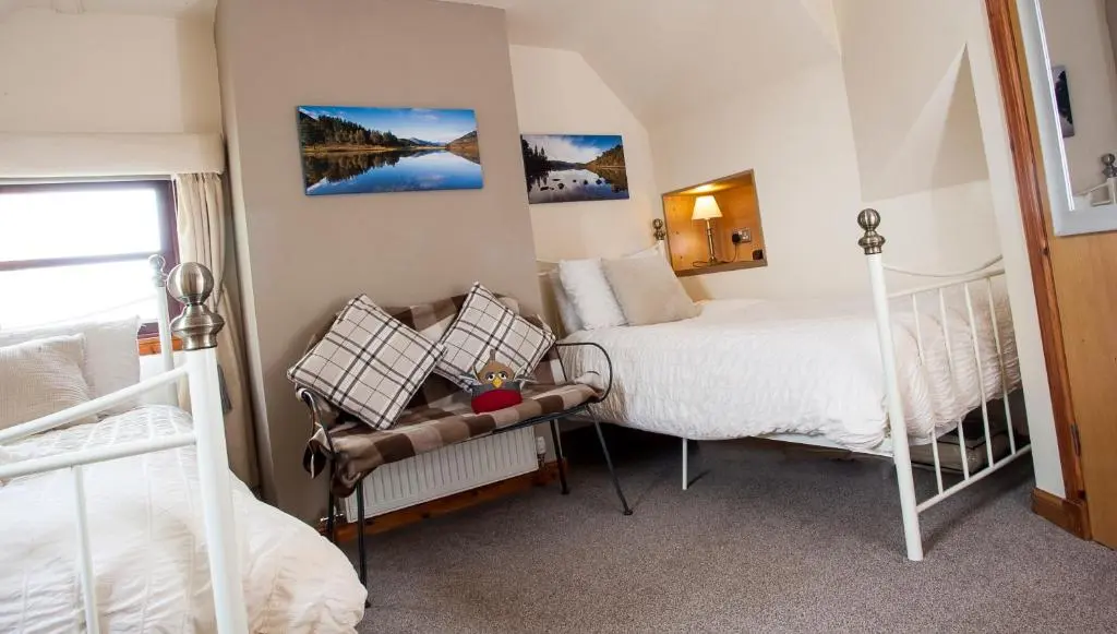a bedroom with two beds and a chair in it at Kettle House B&B in Fort Augustus