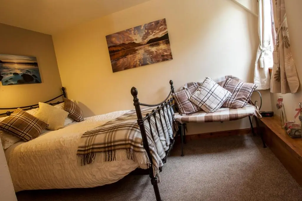 a bedroom with a bed and a chair at Kettle House B&B in Fort Augustus
