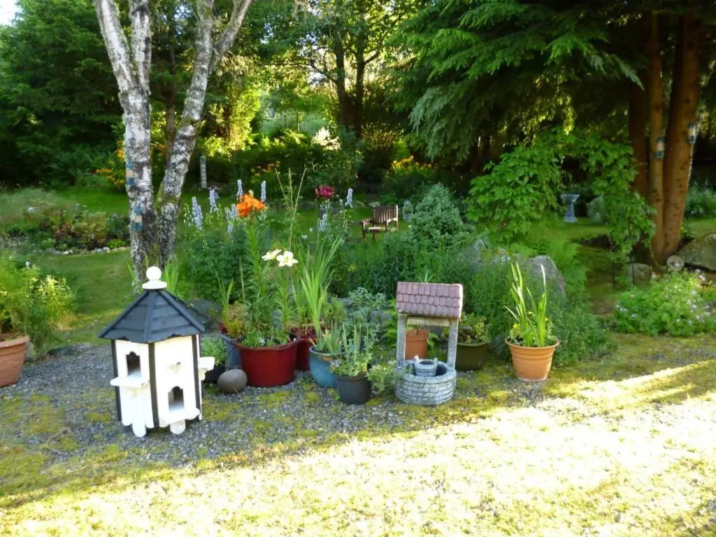 a garden with potted plants and a bird house at Kettle House B&B in Fort Augustus
