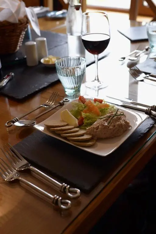 a table with a plate of food and a glass of wine at Binnilidh Mhor B&B in Glenmoriston