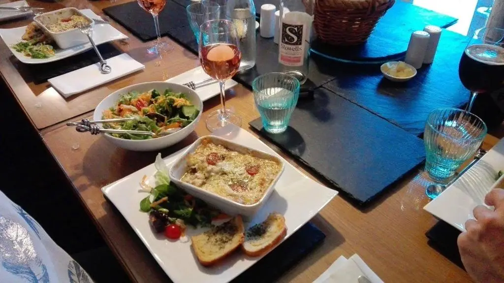 a table with a plate of food and a salad and wine at Binnilidh Mhor B&B in Glenmoriston