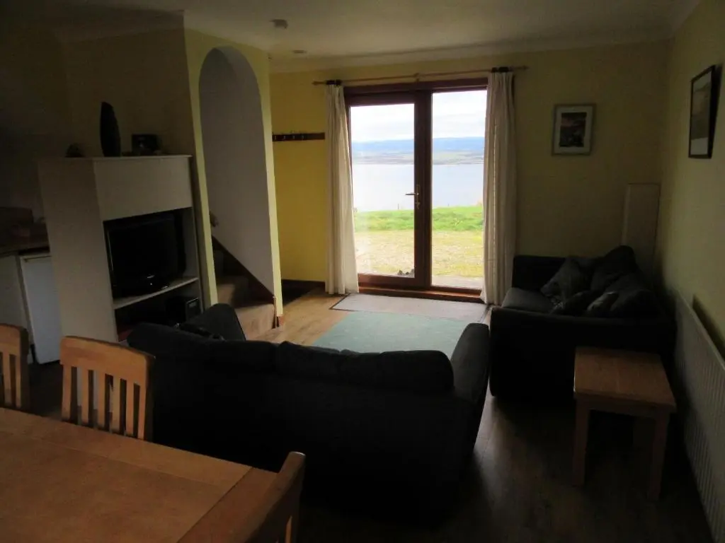 a living room with two couches and a view of the ocean at Osprey, Longhouse Cottages in Rosemarkie