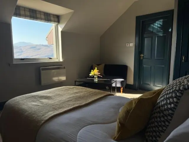 a bedroom with a bed and a window and a door at Ardvreck House in Ullapool
