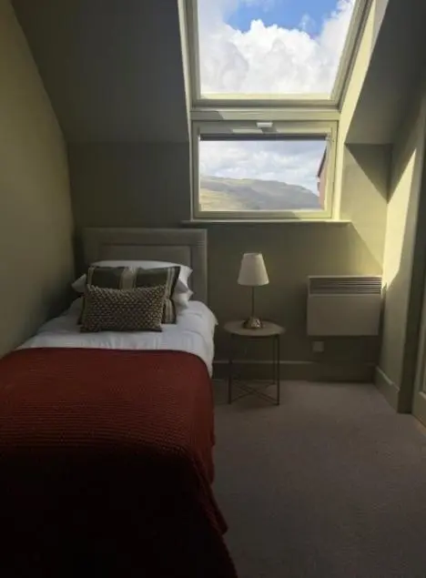 a bedroom with a bed with a large window at Ardvreck House in Ullapool