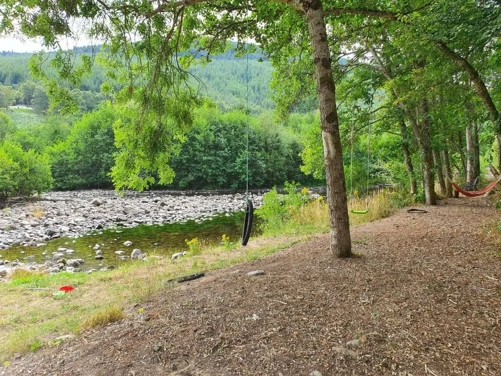a path next to a river with rocks and trees at River Cottage Hot tub spa in Drumnadrochit