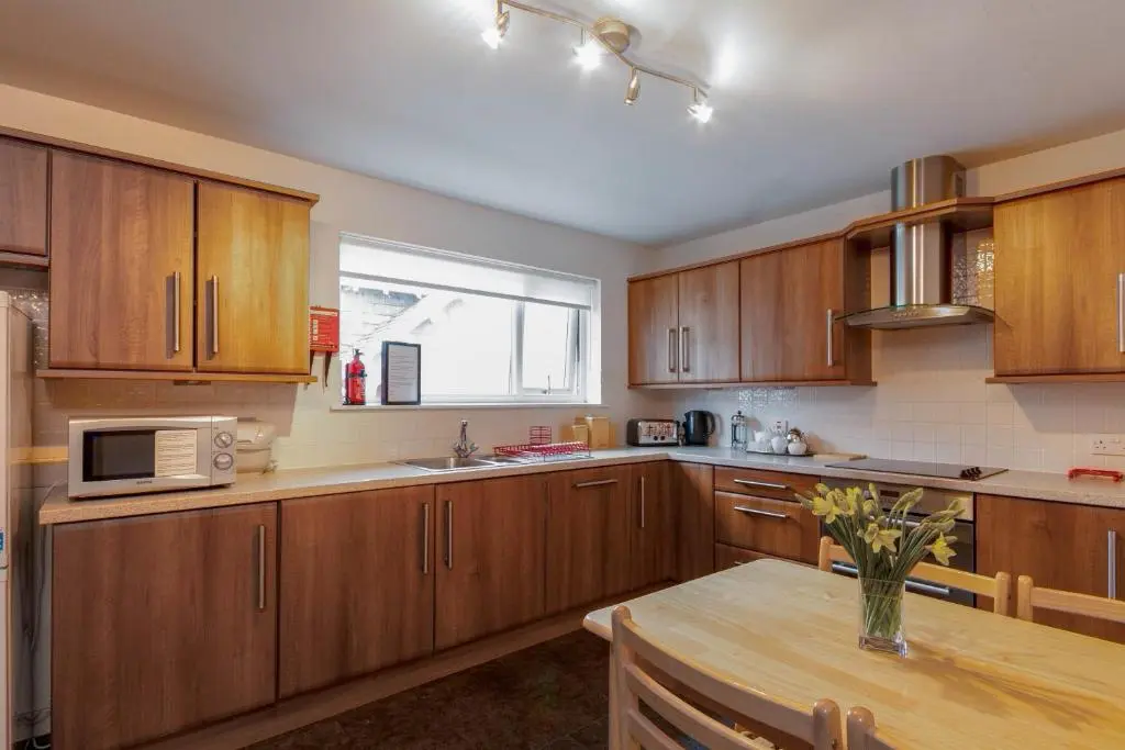 a kitchen with wooden cabinets and a table and a window at Beachview-Holiday Flat 2- Sleeps8 in Lossiemouth