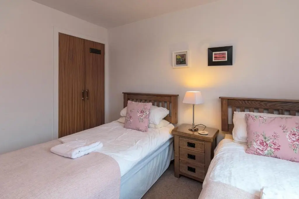 a bedroom with two beds and a lamp on a night stand at Beachview-Holiday Flat 2- Sleeps8 in Lossiemouth
