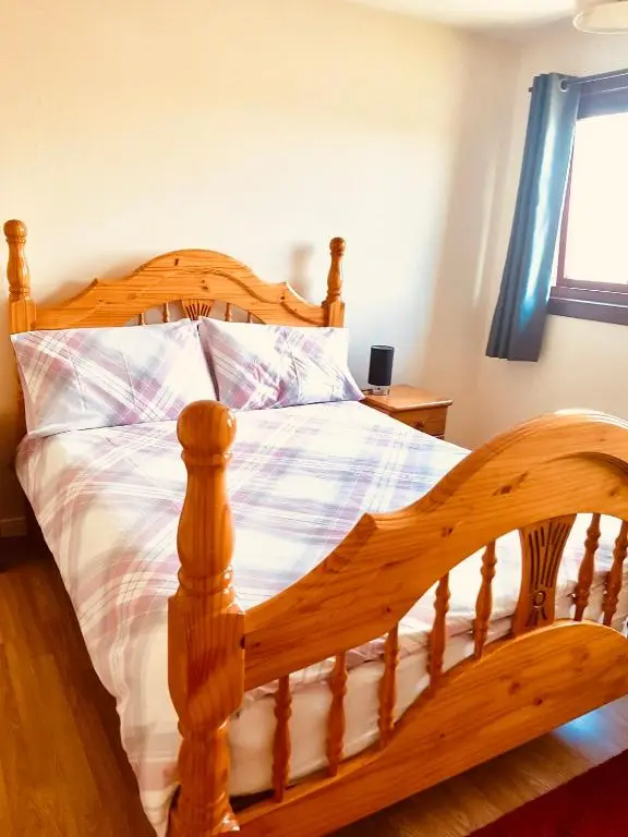 a wooden bed with a wooden frame in a bedroom at Invercaul House in Inverness