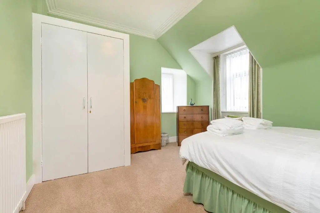 a bedroom with a white bed and a window at Convalmore House in Dufftown