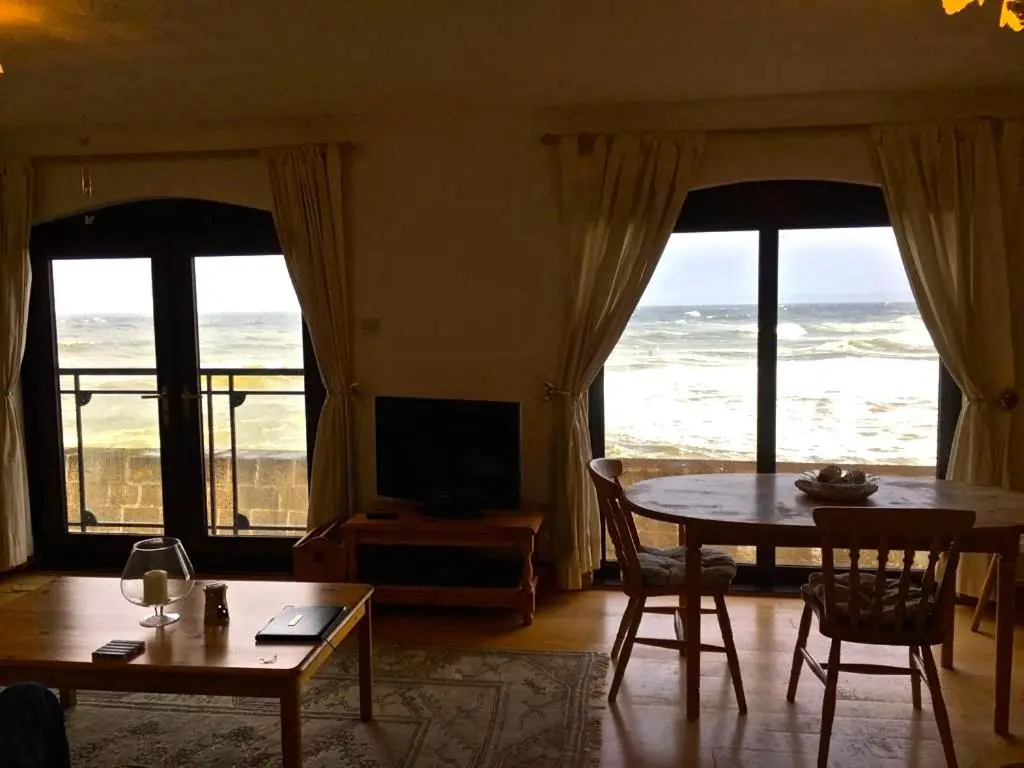 a living room with a table and a view of the ocean at 3 Marina Quay in Lossiemouth