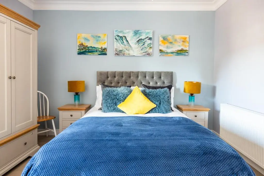 a bedroom with a blue bed and three paintings on the wall at BlueNess in Inverness