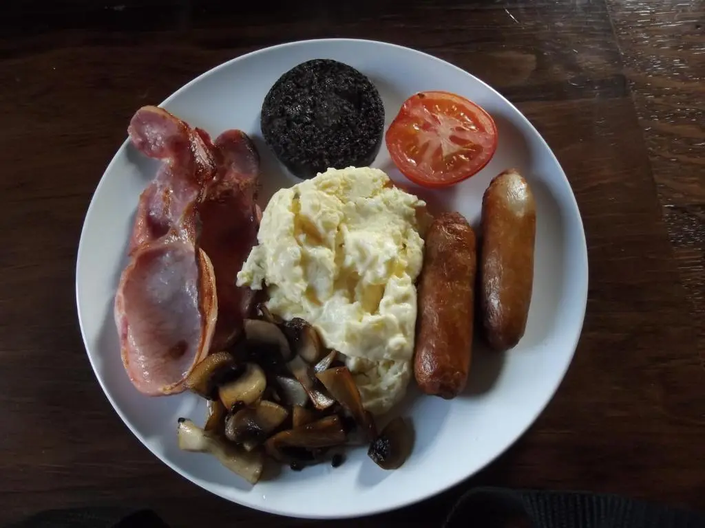 a plate of breakfast food with eggs sausage and tomatoes at Ardmeanach in Inverness