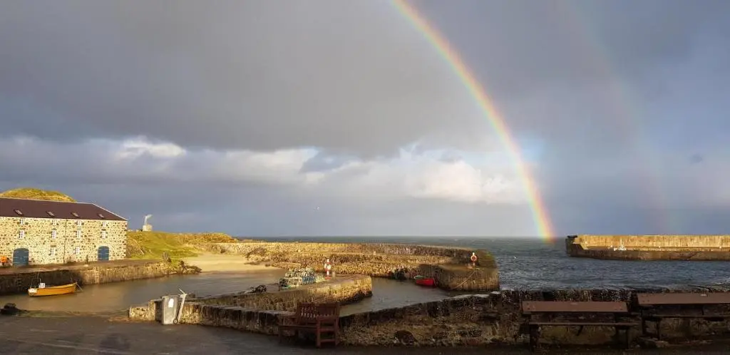 a rainbow over a body of water with a pier at Driftwood Cottage, Portsoy in Banff