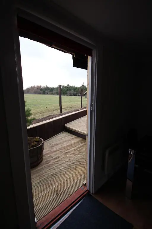 an open door to a deck with a view of a field at Easter Arr Courtyard Apartment in Nairn