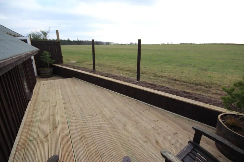 a wooden deck with a view of a field at Easter Arr Courtyard Apartment in Nairn