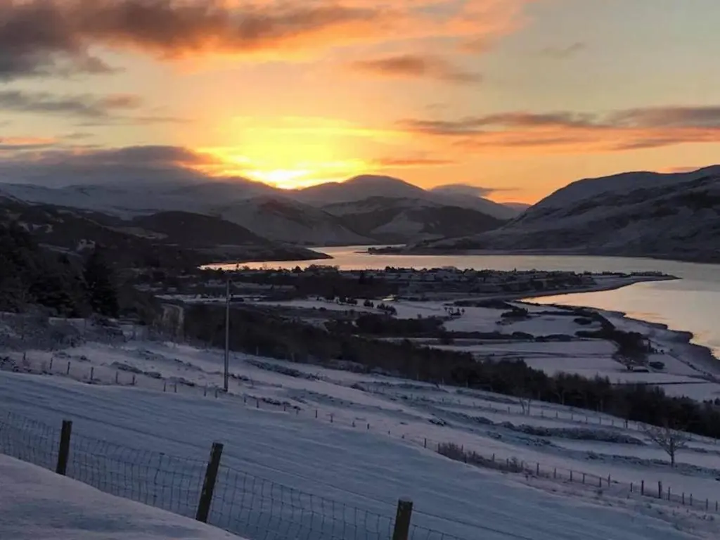 a sunset over a lake in the mountains with snow at Croft No.8 Bed & Breakfast in Ullapool