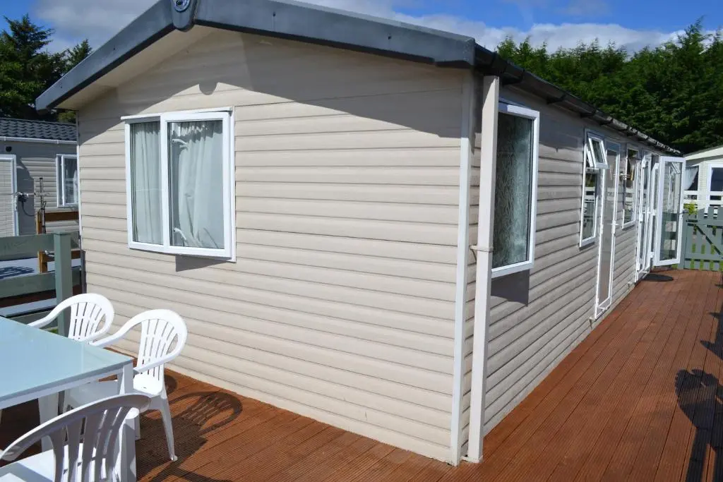 a shed with a table and chairs on a deck at Braemar in Dornoch