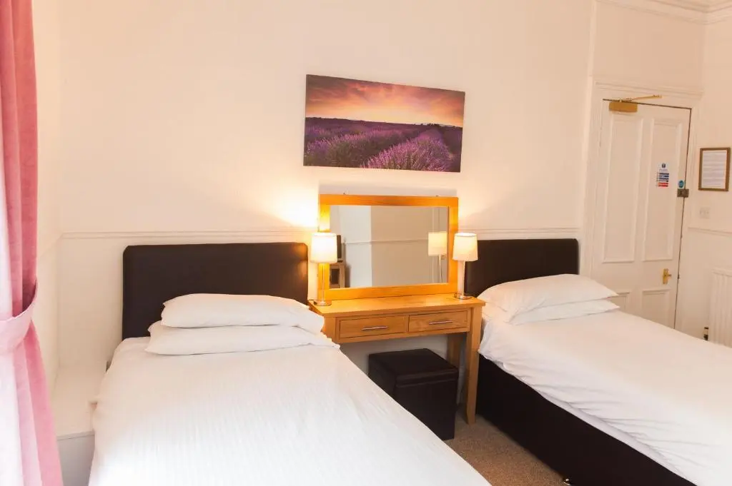 two beds in a room with a mirror at Ardross Glencairn in Inverness