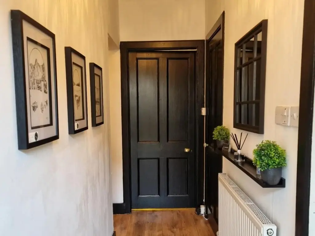 a black door in a hallway with pictures on the wall at Inverness City Centre Flat in Inverness