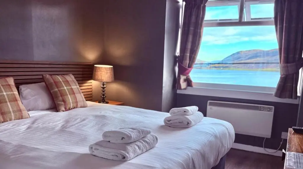 a bedroom with towels on a bed with a window at Argyll Hotel in Ullapool
