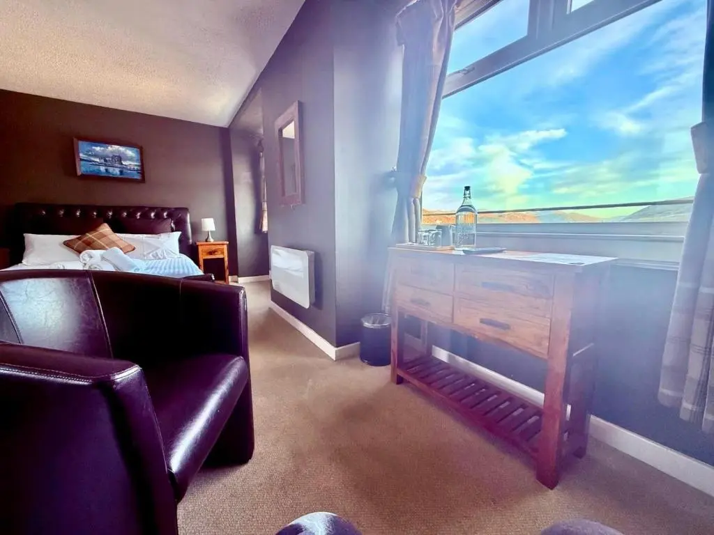 a bedroom with a bed and a large window at Argyll Hotel in Ullapool