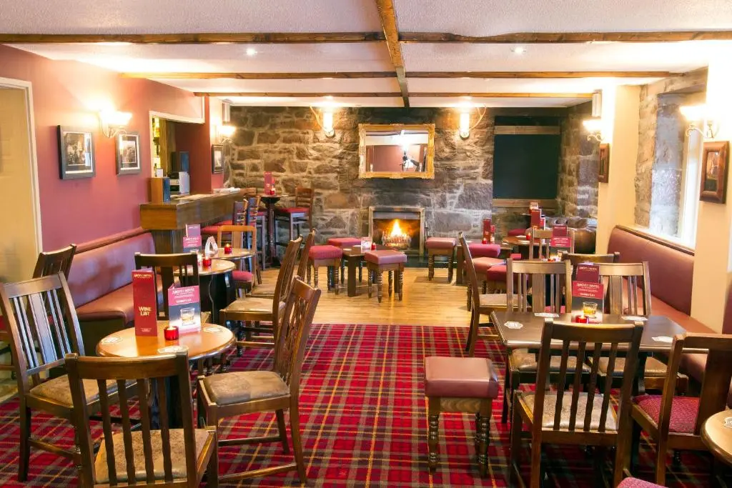 a restaurant with tables and chairs and a fireplace at Argyll Hotel in Ullapool