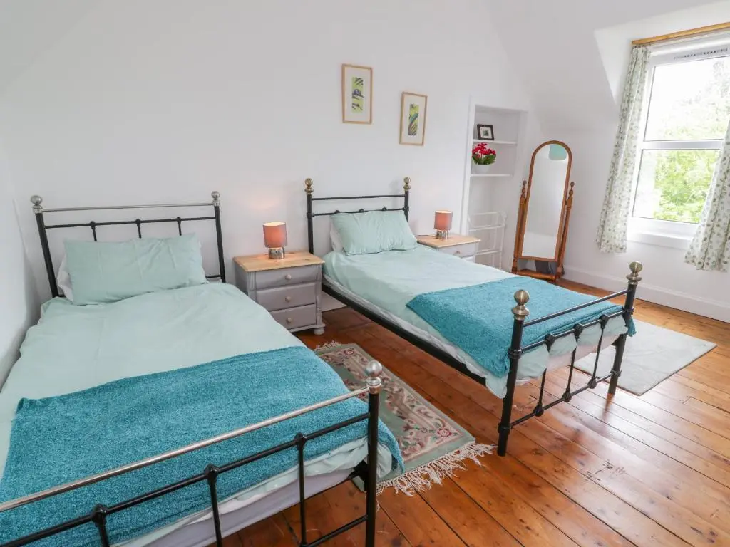 a bedroom with two twin beds and a mirror at Church View in Kingussie