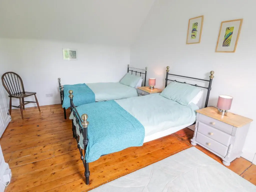 two beds in a bedroom with a desk and a chair at Church View in Kingussie