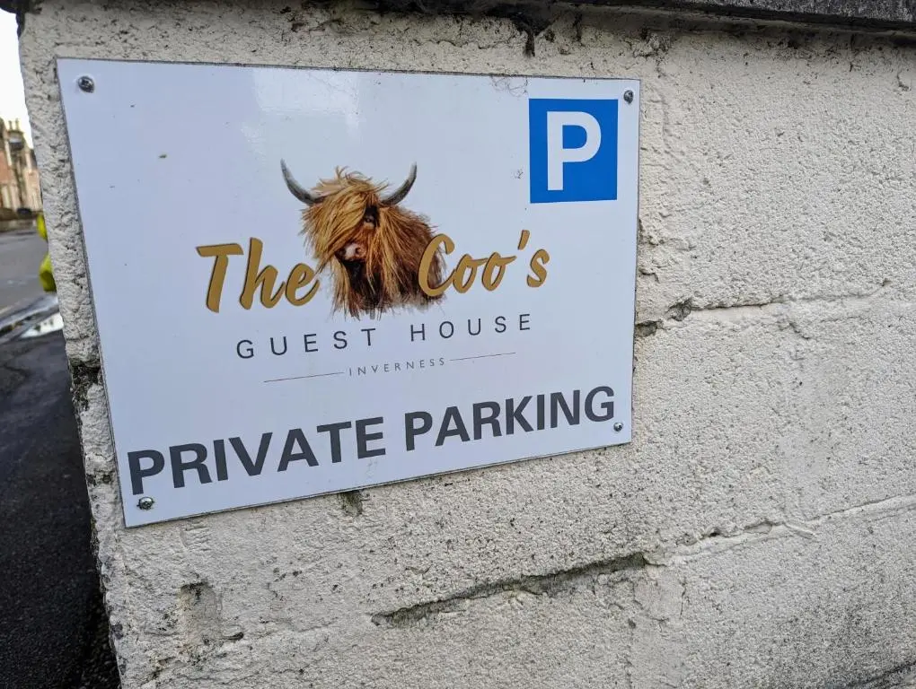 a sign for a guest house with a cow on a wall at The Coo's Guest House in Inverness