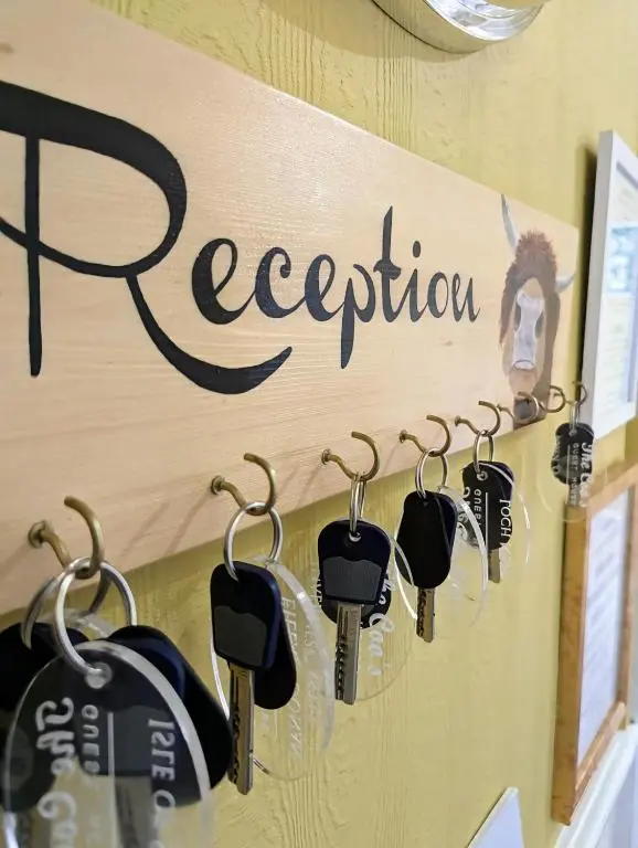 a row of key hooks on a wall with the word reception at The Coo's Guest House in Inverness