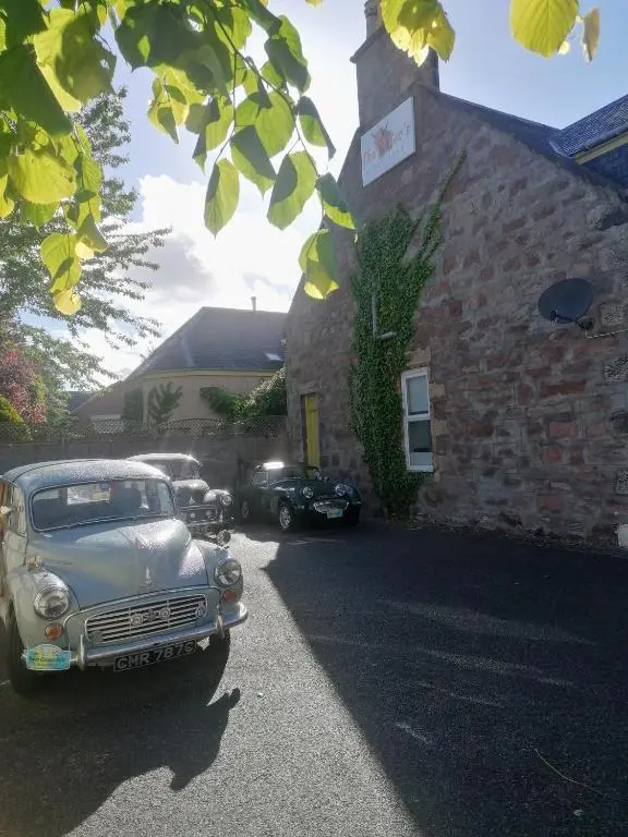 two old cars parked in front of a building at The Coo's Guest House in Inverness