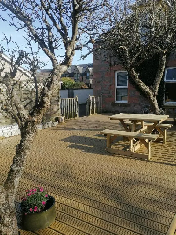 a wooden deck with a picnic table and a tree at The Coo's Guest House in Inverness