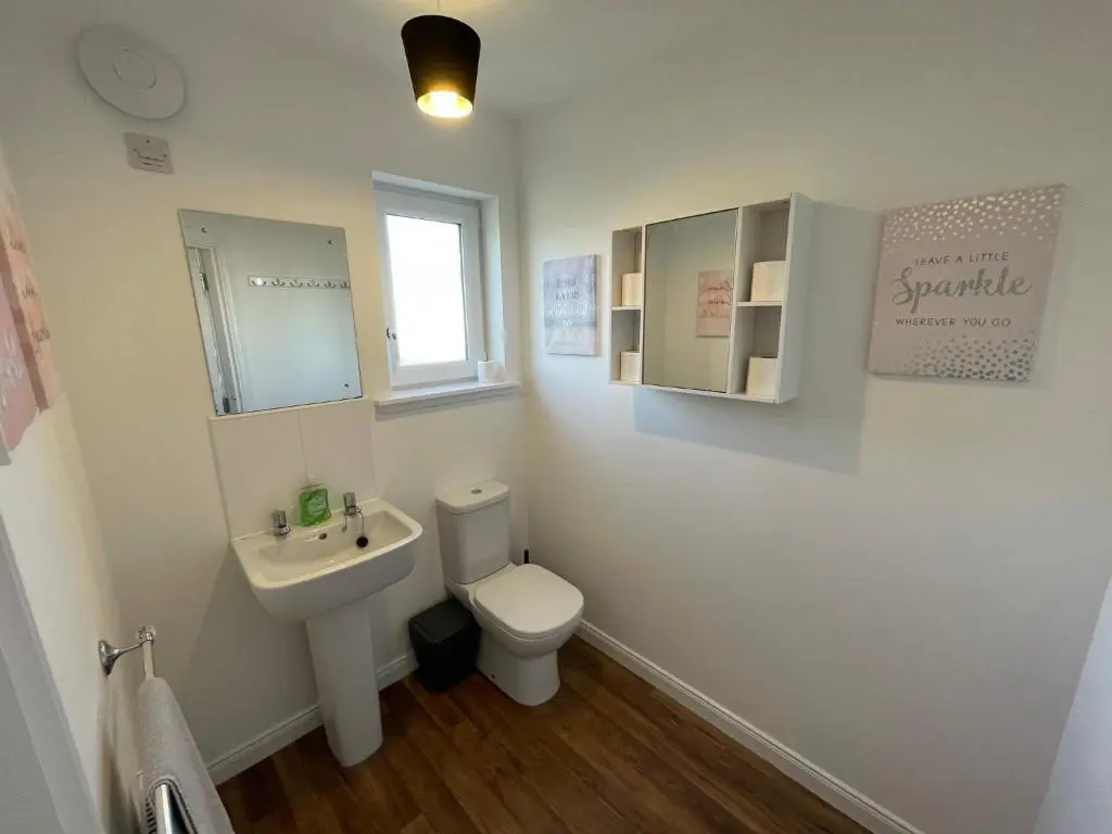a bathroom with a toilet and a sink and a mirror at Gorsebank View in Inverness