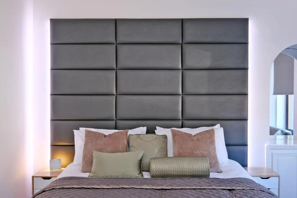 a bedroom with a large black padded headboard at Ben Shea Smart Home in Dufftown