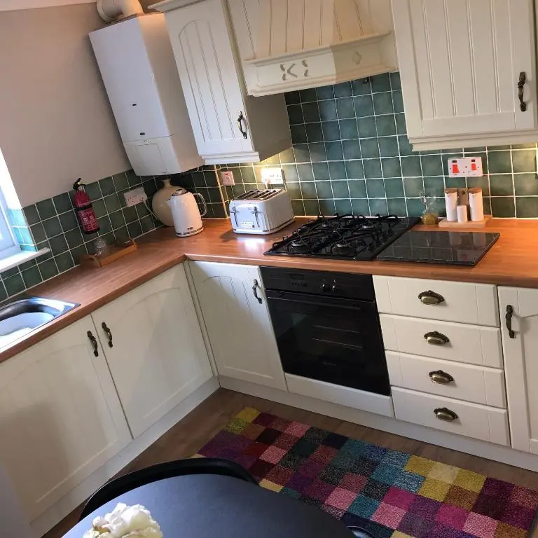a kitchen with white cabinets and a black stove top oven at The Maples 26 Wellingtonia Court in Inverness