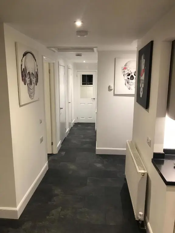 a hallway with white walls and black tile floors at L&H APARTMENTS in Inverness