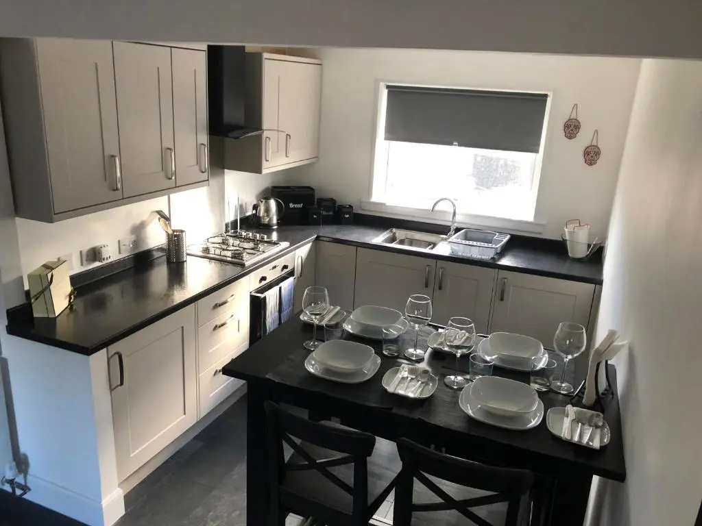 a kitchen with a table with plates and glasses on it at L&H APARTMENTS in Inverness