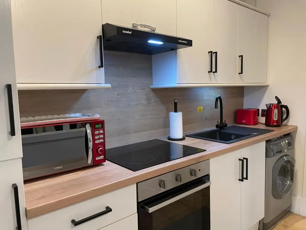 a kitchen with white cabinets and a red microwave at The King Street Holiday Apartment in Inverness City Centre in Inverness