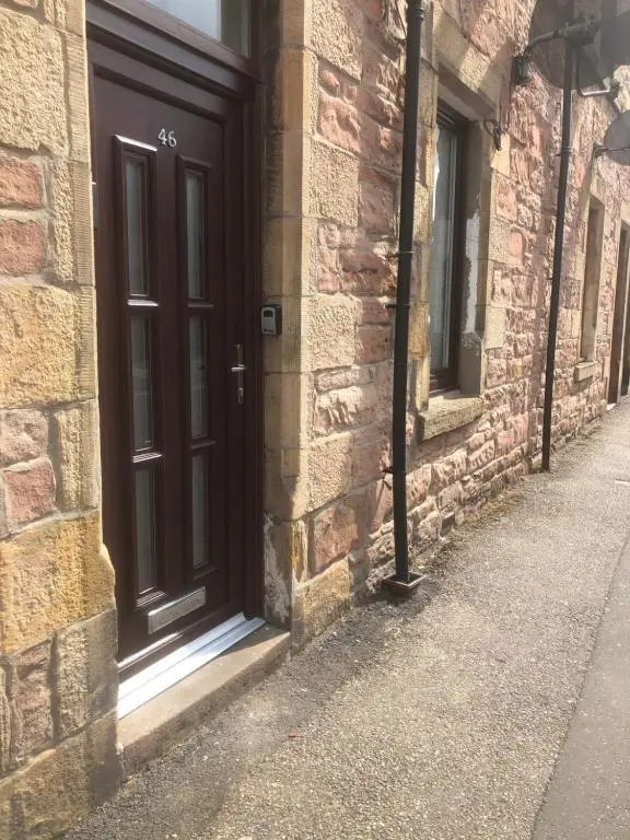 a brown door on the side of a brick building at The King Street Holiday Apartment in Inverness City Centre in Inverness