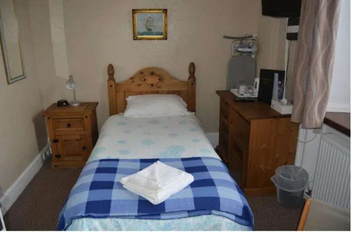 a bedroom with a blue and white bed and wooden furniture at Queens hotel in Wick