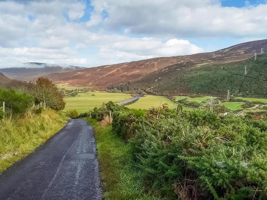 a road in the middle of a valley with mountains at Farr in Helmsdale