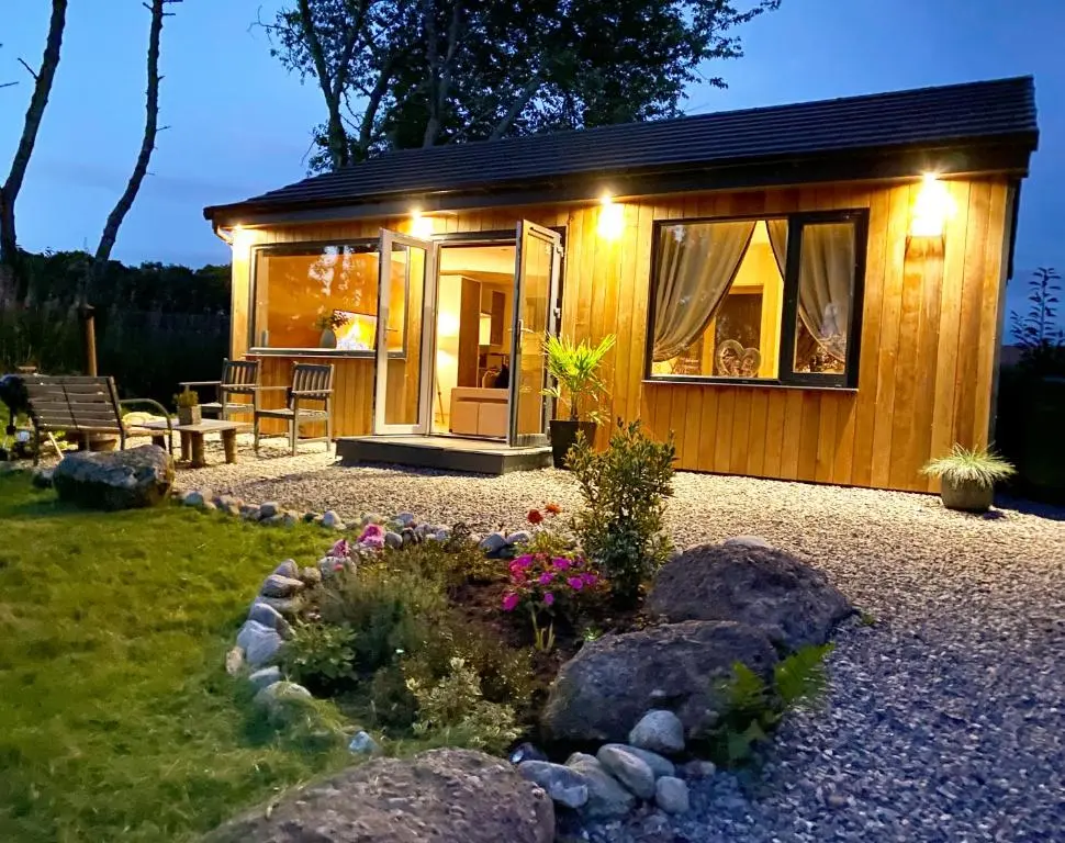 a small wooden cabin with lights on it at Druid House Lodge in Inverness