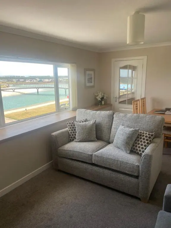 a living room with a couch and a large window at The Jewel of the Moray Firth in Lossiemouth