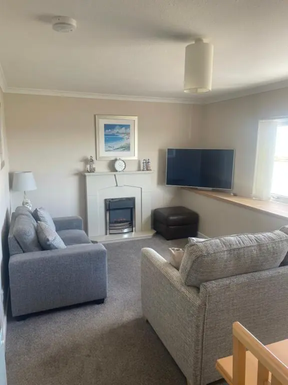 a living room with two couches and a flat screen tv at The Jewel of the Moray Firth in Lossiemouth