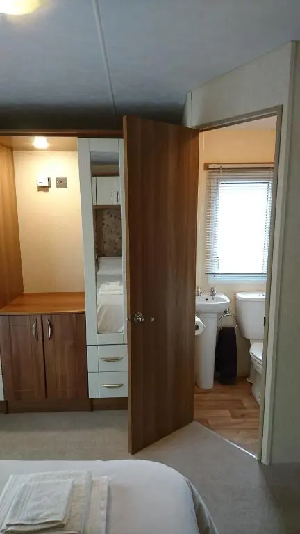 a bedroom with a bed and a bathroom with a sink at No42 Wild Goose in Dornoch