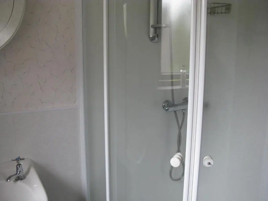 a shower with a glass door in a bathroom at Greenfield Cottage in Thrumster