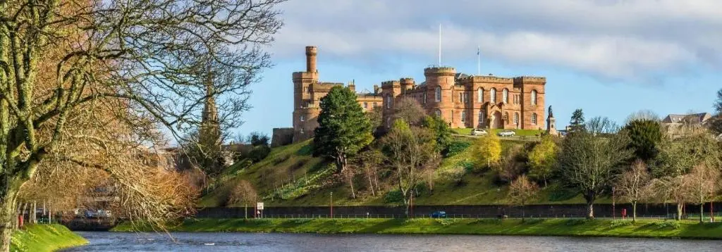 a castle on top of a hill next to a river at Bosta B&B in Inverness